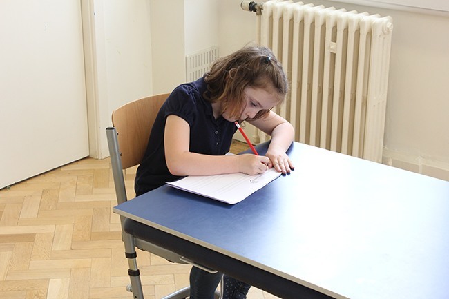 Child writing on a sloped writing board, leaning forward