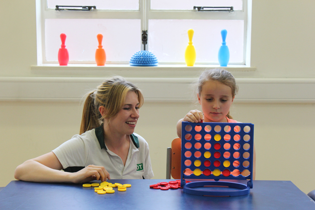 Therapist playing connect four with a young girl