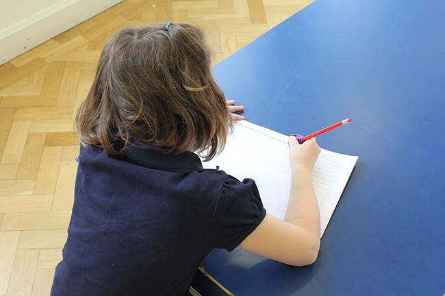 Child writing, over the shoulder angle