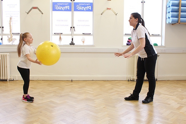 Child and Therapist throwing a large ball to each other